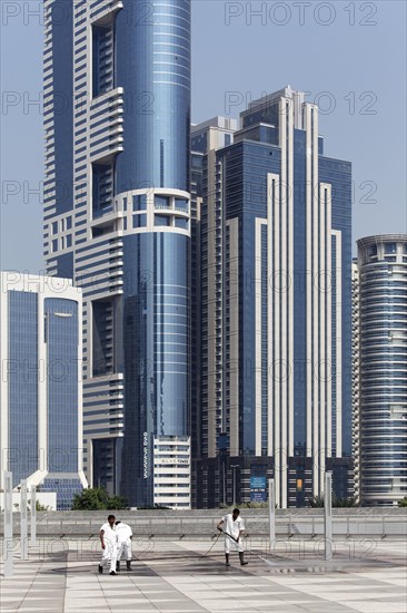 Workers cleaning a terrace in front of skyscrapers with a high pressure washer