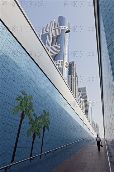 Single person walking through a pedestrian underpass with painted palm trees