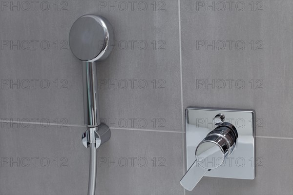 Modern shower head and bathroom fitting on tiled wall