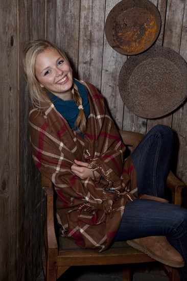 Smiling young woman wrapped in a blanket in a hiking hut