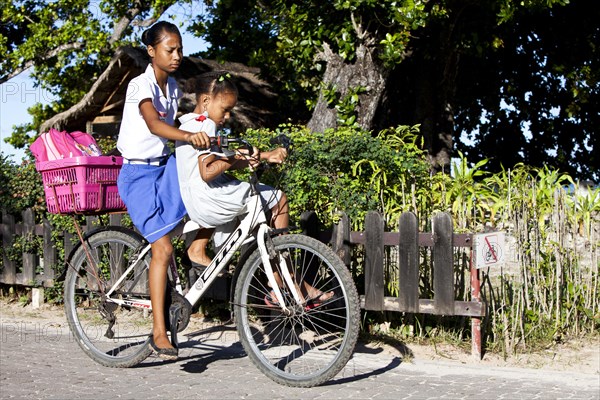 Two girls riding on one bike