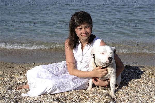 Girl sitting on the beach with a Staffordshire Bull Terrier