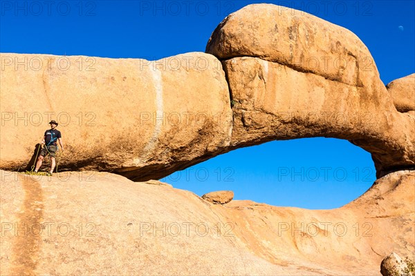 Young man climbing a rock arch