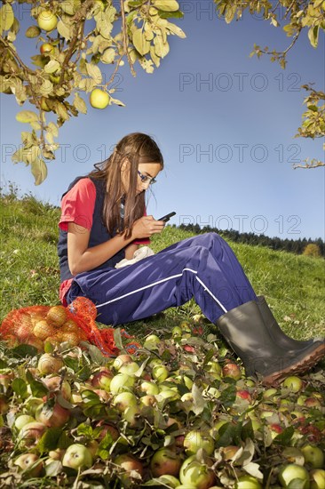 Girl with mobile phone in orchard