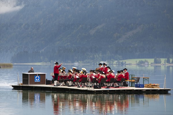 The Weissensee marching band in traditional costumes performing on a raft at the Naturparkfest festival in Techendorf