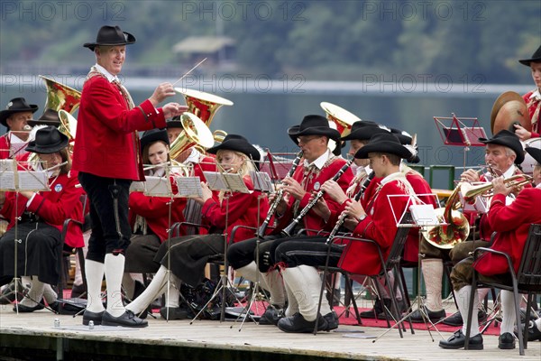 The Weissensee marching band in traditional costumes with conductor Johann Knaller performing on a raft at the Naturparkfest festival in Techendorf