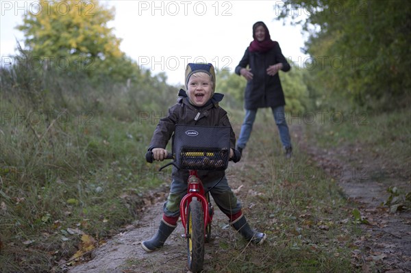 Little boy is riding his bicycle down a forest path