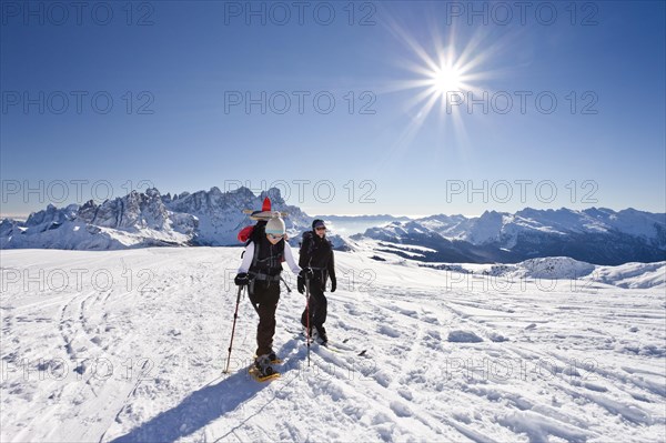 Snowshoe hiker and a cross-country skier ascending Uribrutto Mountain