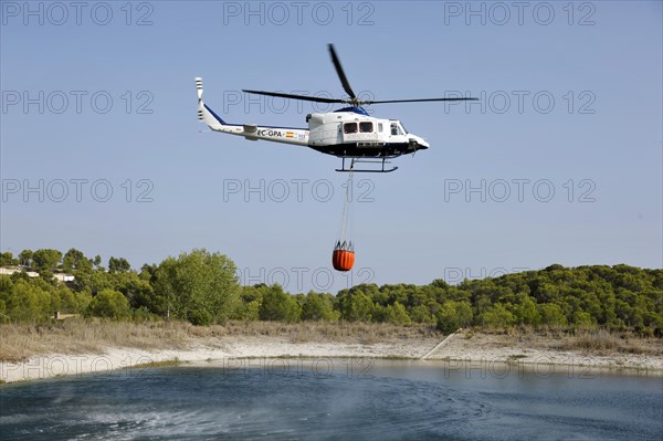 Fire helicopter getting water from a small artificial lake near Altea La Vella