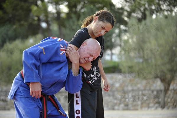 Student keeps her martial arts instructor in a headlock during a training session in a park