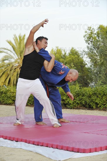 Two men doing martial arts training in a park