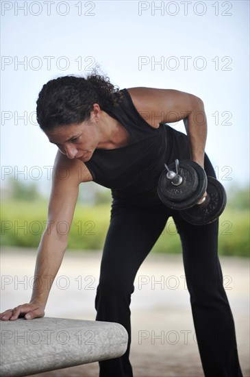 Woman lifting weights while exercising in a park
