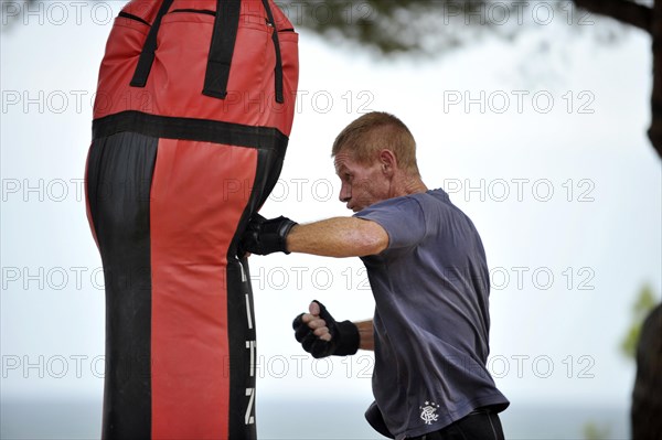 Man practicing punches on a punching bag in a park