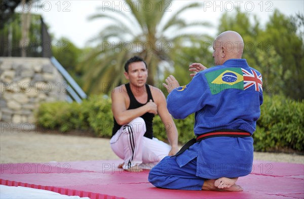 A martial arts instructor is giving instructions to a student during a training session in a park