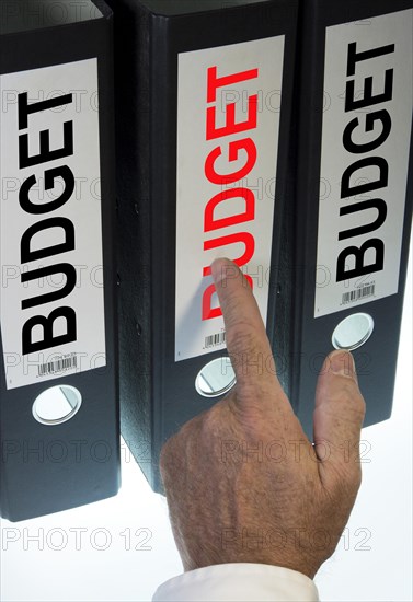 Hand pointing to a ring binder labelled 'BUDGET'