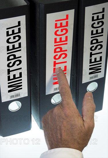 Hand pointing to a file folder labeled 'Mietspiegel'