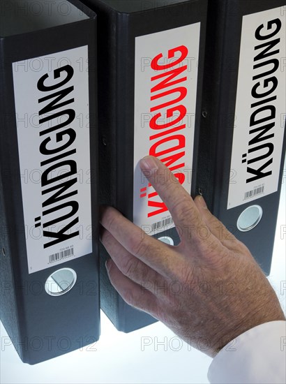 Hand reaching for a file folder labeled 'Kuendigung'