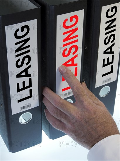 Hand reaching for a ring binder labelled 'LEASING'