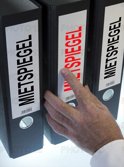 Hand pointing to a file folder labeled 'Mietspiegel'