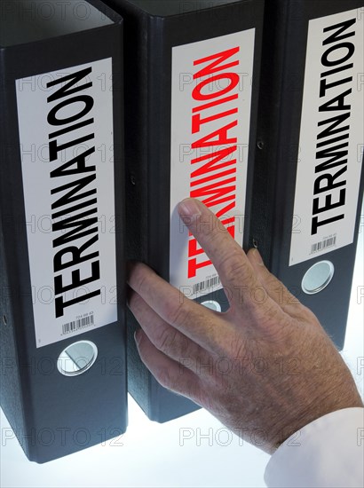 Hand reaching for a file folder labeled 'Kuendigung'