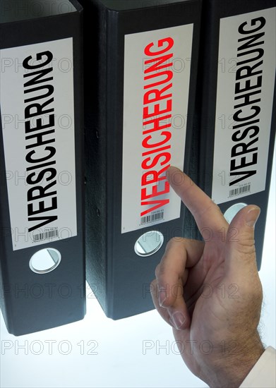 Hand pointing to a ring binder labelled 'VERSICHERUNG'