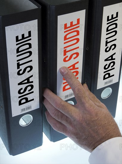 Hand reaching for a file folder labeled 'PISA-Studie'