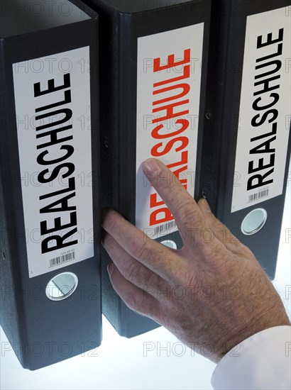 Hand reaching for a file folder labeled 'Realschule'