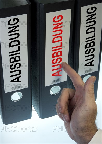 Hand pointing to a file folder labeled 'Ausbildung'