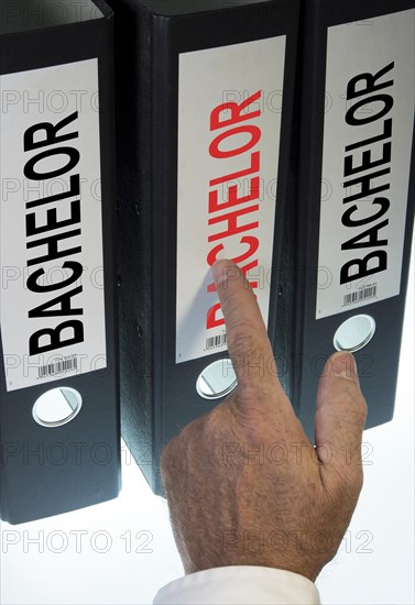 Hand pointing to a file folder labeled 'Bachelor'