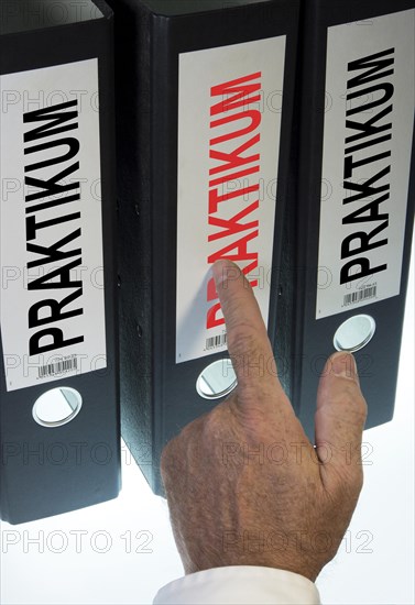 Hand pointing to a file folder labeled "Praktikum"