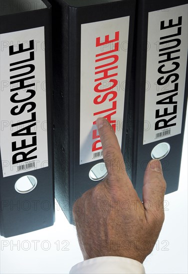 Hand pointing to a file folder labeled 'Realschule'