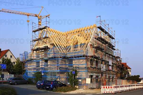 Shell of a multistory apartment building with finished roof and construction crane