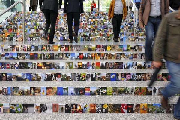 People walking on stairs covered with photos