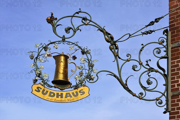 Hanging sign from the restaurant Sudhaus against a blue sky