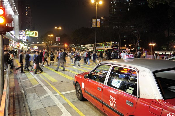 A red taxi waiting at a zebra crossing on Chatham Road in the evening