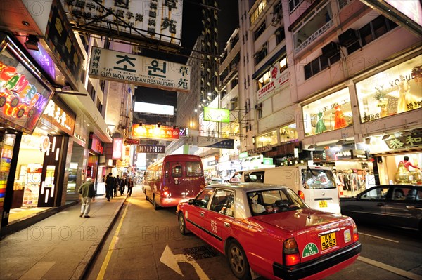 A red taxi on a street in the Tsim Sha Tsui district in the evening