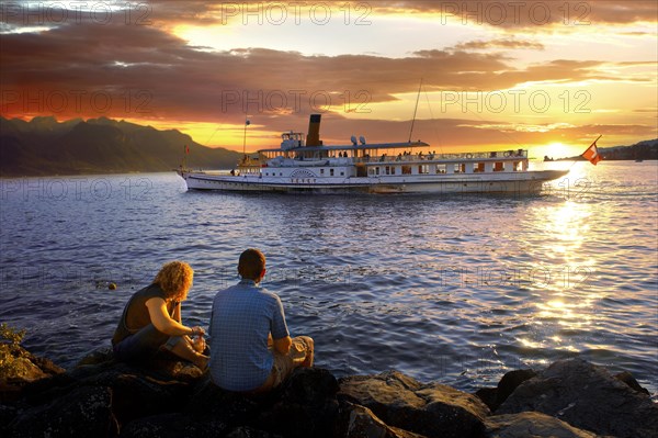 Youg couple watching a ferry at sunset on Lac Leman