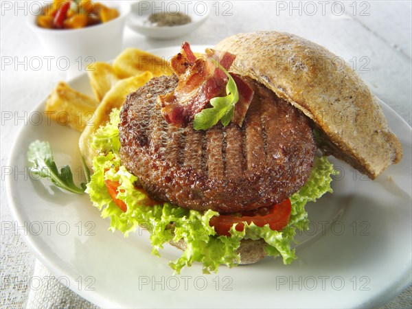 Beef burger with bacon in a wholemeal bun with salad and french fries