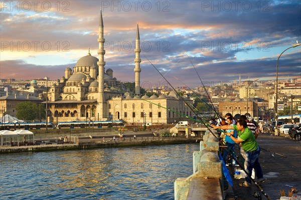 Fisherman on the Galata bridge fishing in the Golden Horn next to The Yeni Camii