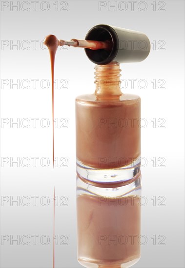 Pink nail varnish dripping from a nail varnish brush balanced on a nail varnish bottle