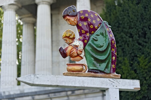 Grandmother with a child on a potty as a guide to the toilet in front of the Hall of Fame at the Wies'n