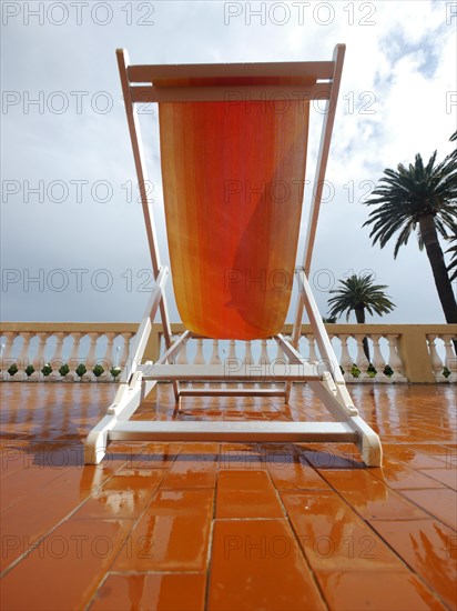 Deck chair on a porch under palm trees