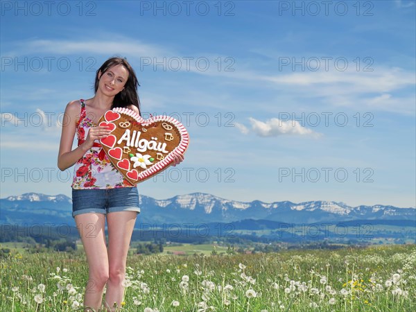 Woman holding a gingerbread heart labelled with the word Allgaeu