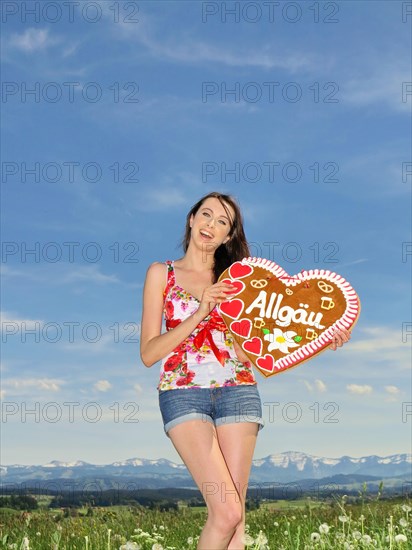 Woman holding a gingerbread heart labelled with the word Allgaeu