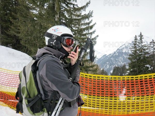 Skier on a barrier speaks in their smartphone