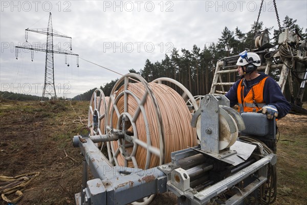 Lineman working with a wire rope hoist on a 380-kV long-distance line owned by the 50Hertz transmission system operator