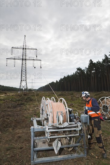 Lineman working with a wire rope hoist on a 380-kV long-distance line owned by the 50Hertz transmission system operator