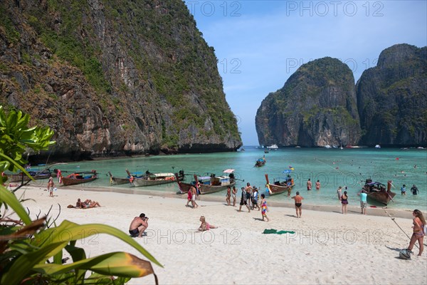 Tourists and longtail boats on the sandy beach of Maya Beach
