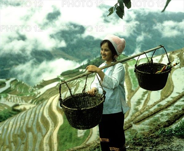 Woman carrying baskets with a shoulder pole