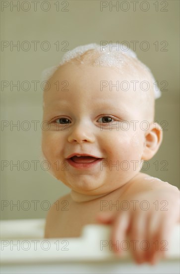 Baby in a bath with foam on his head